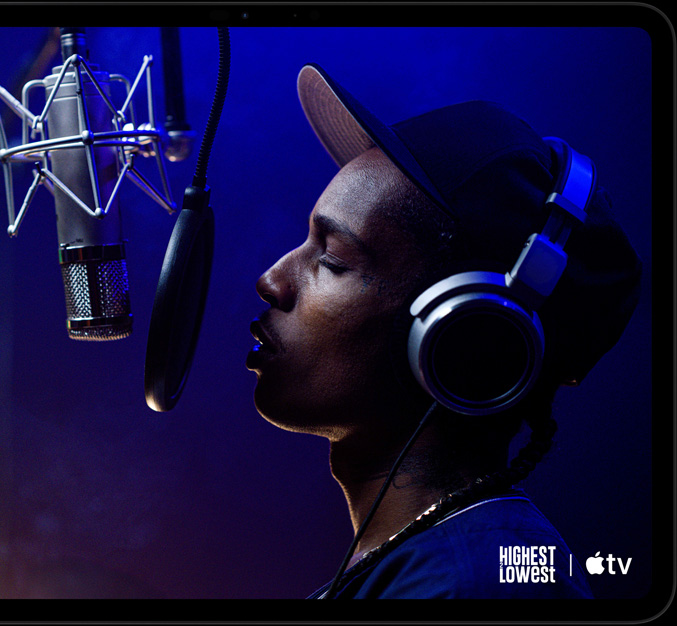 iPad Pro, landscape orientation, front exterior, space black color, rounded corners, black display bezel, display showing Apple TV playing a scene from  the Apple TV original film Highest 2 Lowest with ASAP Rocky as Yung Felon rapping into a microphone
